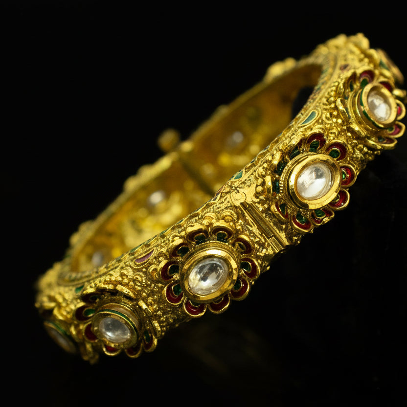 Gold bracelet with gemstones on a dark background, featuring the brand 'Saheli'.