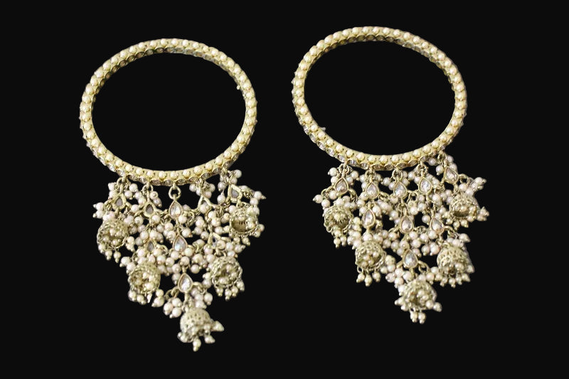 Pair of gold chokers with floral pendants on a black background