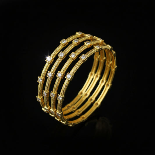 Gold bangles with embedded stones on a black stand, branded 'SAHELL'.