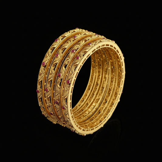 Gold bangles with red stones on a gray background, featuring the brand 'Saheli'.