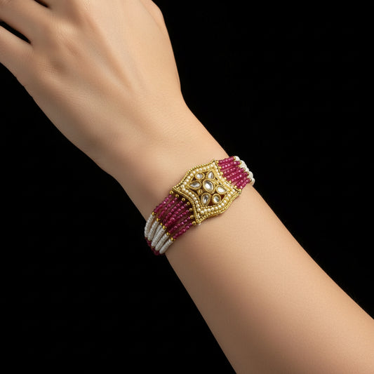 Bracelet with gold clasp and pink and white beaded strands on a dark background, featuring the brand 'Saheeli'.