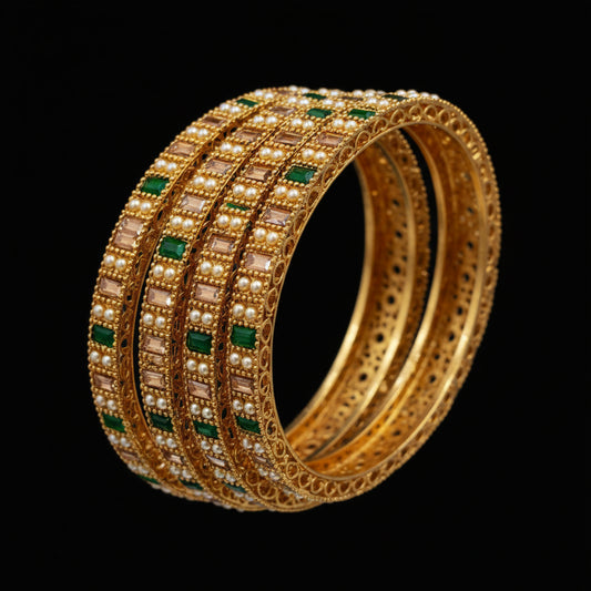 Gold bangles with green stones on a hand, with a blurred background