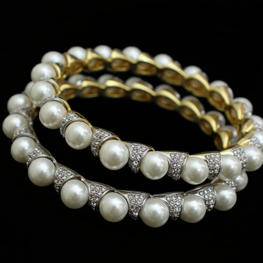 Pearl bangles with gold accents on a black stand, branded 'SAHELI'.