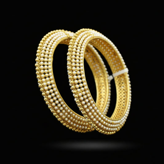 Gold bangles on a black stand with 'SAHELI' branding.