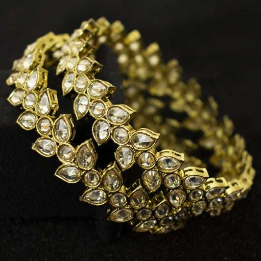 Gold bracelet with diamond-like stones on a black background, featuring the brand 'Saheli'.