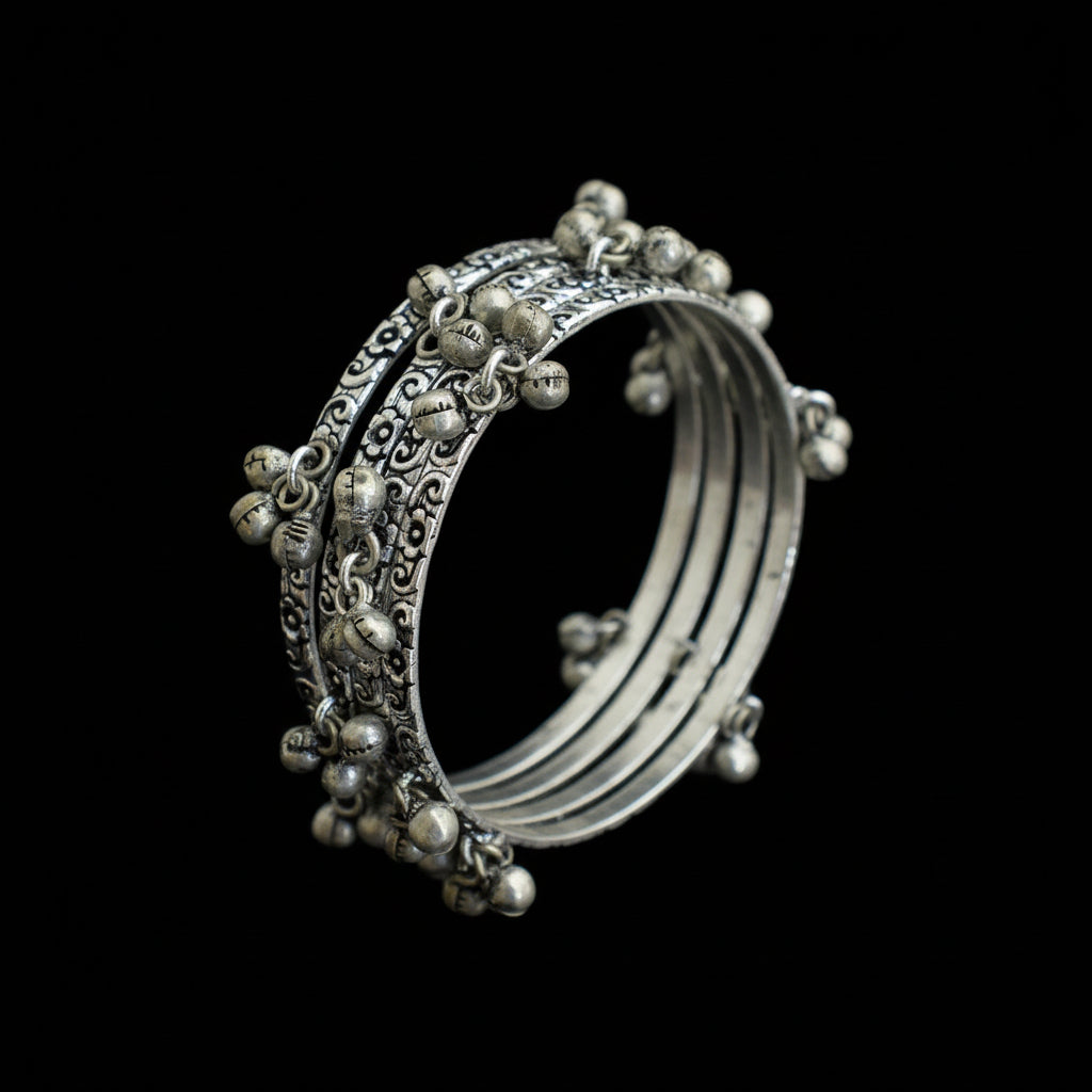 Silver bangles with intricate designs on a gray stand, branded 'Saheli'.