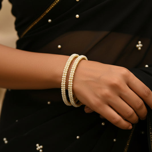 Gold and pearl bracelet on a black stand with 'Saheli' branding.