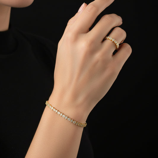 Gold bracelet and ring on a gray jewelry display pillow with a dark background