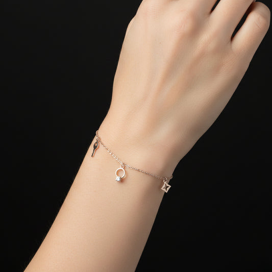 Silver necklace with key, circular, and star-shaped charms on a dark background