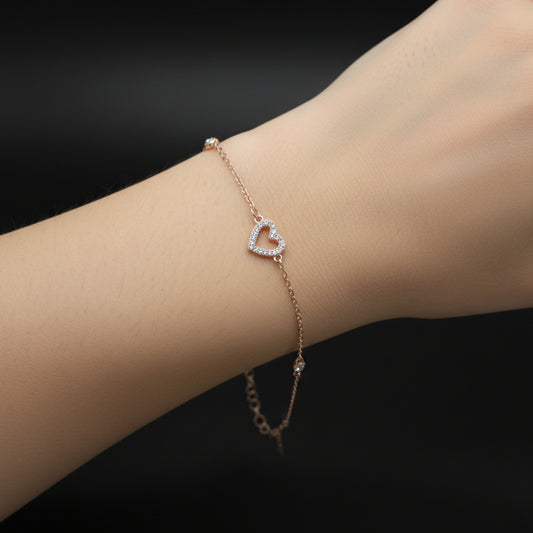Gold bracelet with a heart-shaped clasp on a dark background