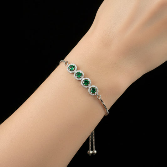 Silver bracelet with green gemstones on a black background