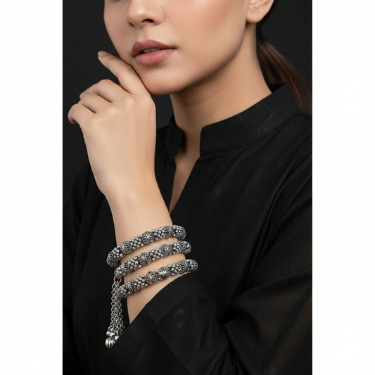 Silver bangles with jhumkas on a black background, featuring the brand 'Saheli'.