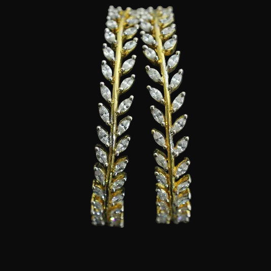 Gold and diamond leaf-shaped earrings on a black background with 'SAHELI' branding.
