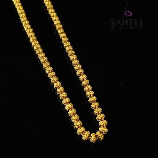 Gold chain necklace on a gray background with 'SAHELI' branding.