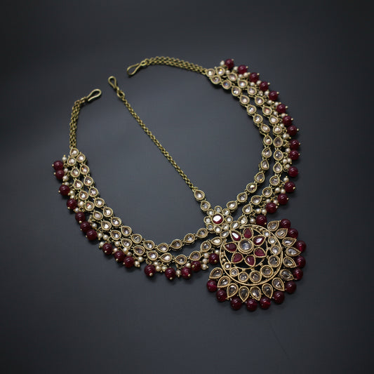Ornate necklace with red and gold beads on a dark background