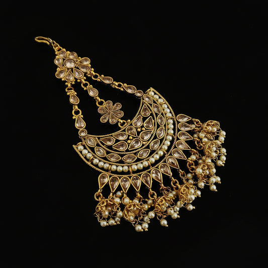 Gold necklace with floral designs on a dark background, featuring the brand 'Saheli'.