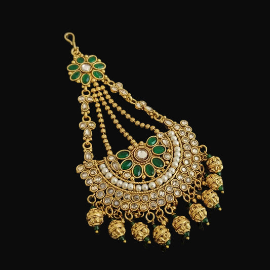 Ornate gold and green jewelry piece on a dark background