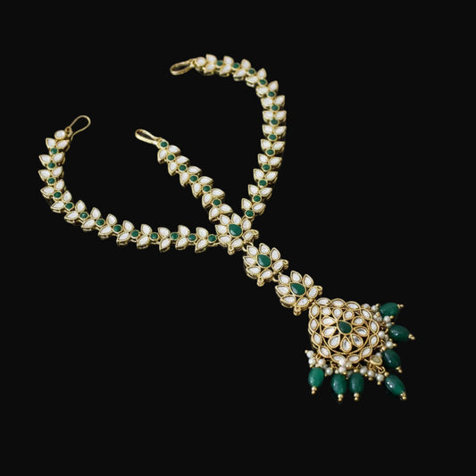 Ornate necklace with green and gold details on a dark background