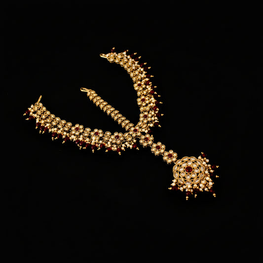 Ornate necklace with red stones on a dark background, featuring the brand 'Saheli'.
