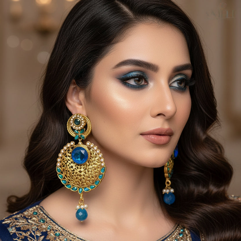 Pair of gold and blue earrings on a gray background with 'SAHELI' branding.