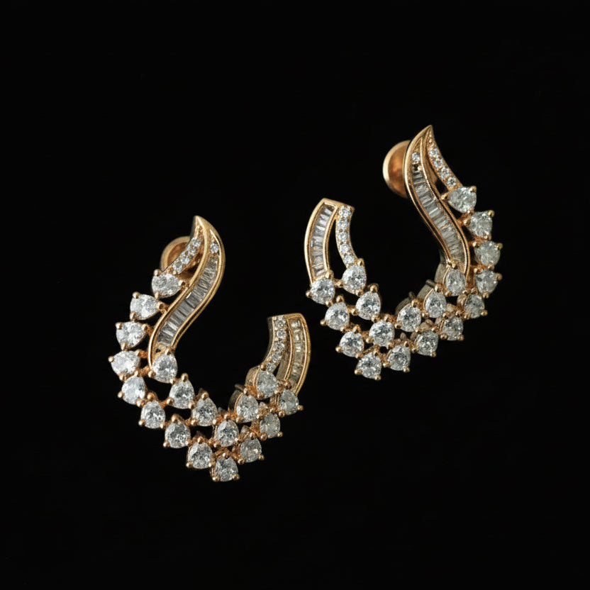 Gold and diamond earrings with a brand card on a black background