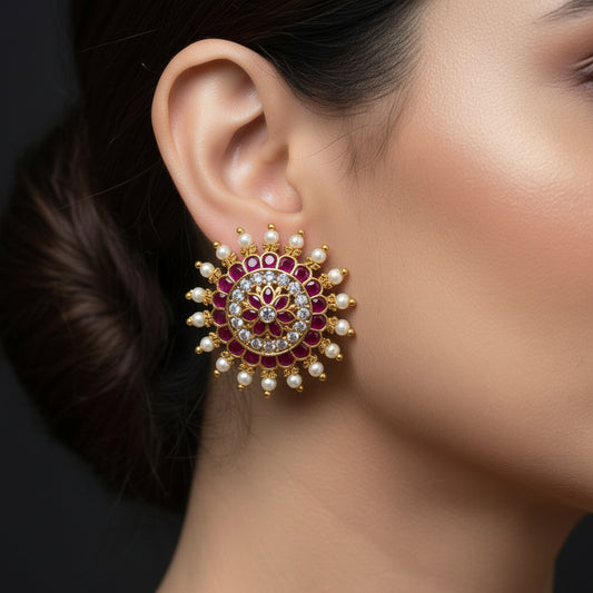 Ornate earrings with gemstones on a black background, branded 'Saheli'.