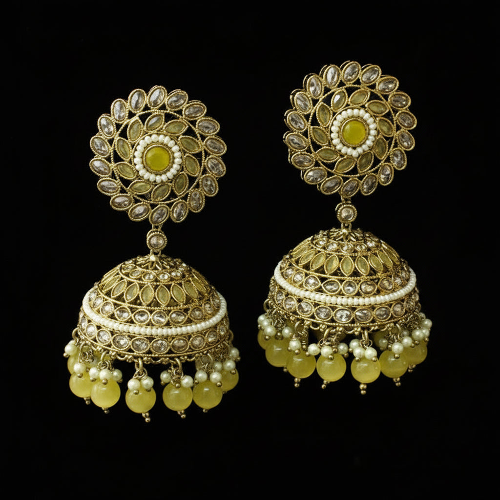Gold and green earrings on a black stand against a black background