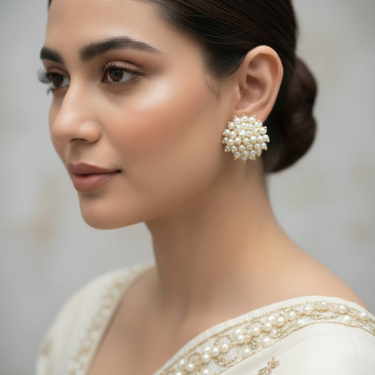 Pearl earrings on a black stand with 'Saheli' branding.
