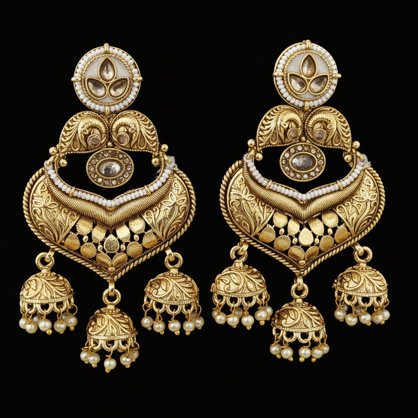 Ornate gold earrings with intricate designs on a textured black and gray background.