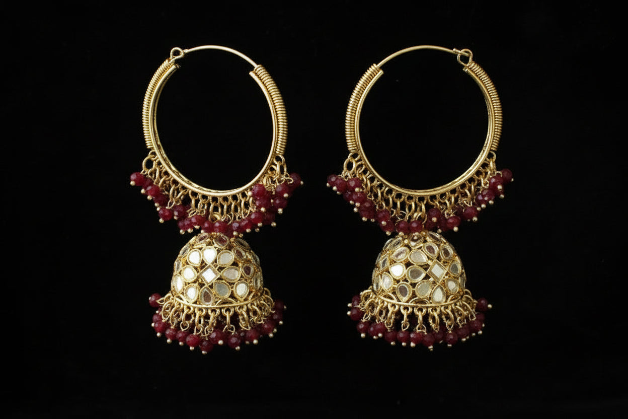 Pair of gold and red earrings on a black stand