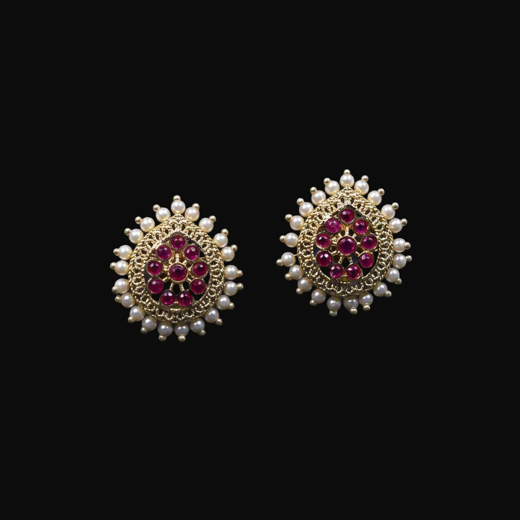 Gold and red gemstone earrings on a black stand with 'Saheli' branding.