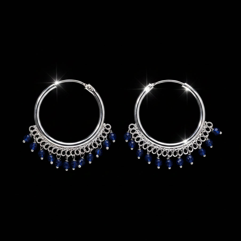Pair of silver hoop earrings with blue beads on a brown background
