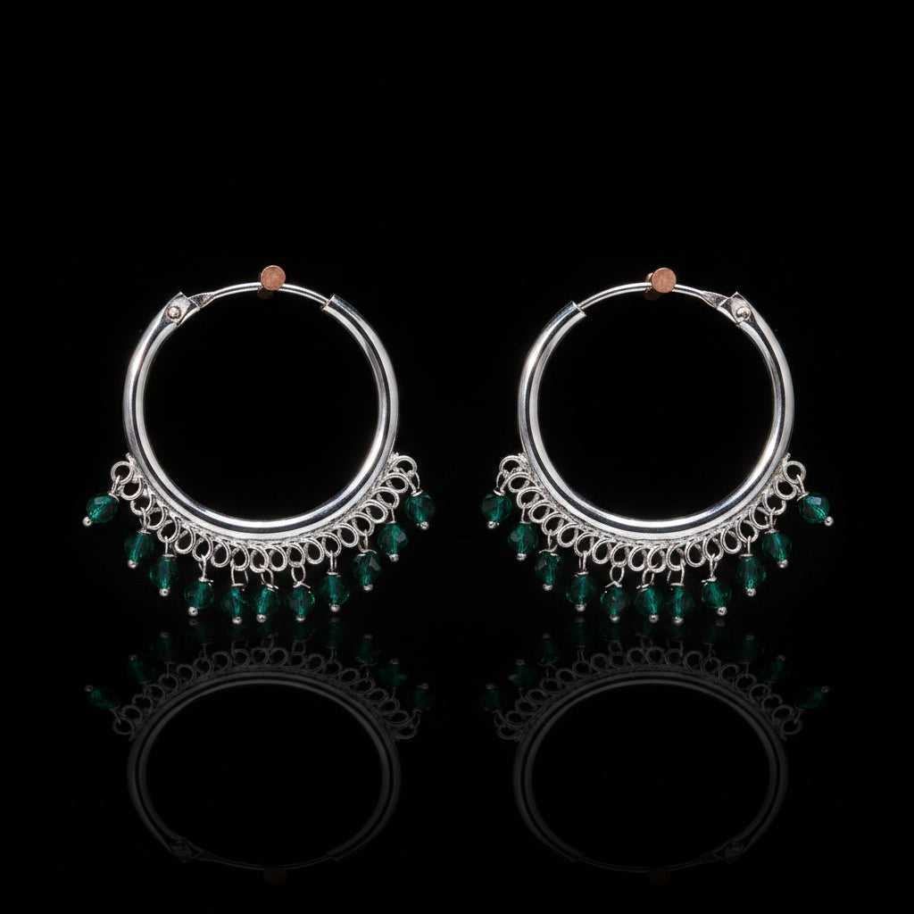 Pair of silver hoop earrings with green beads on a brown background