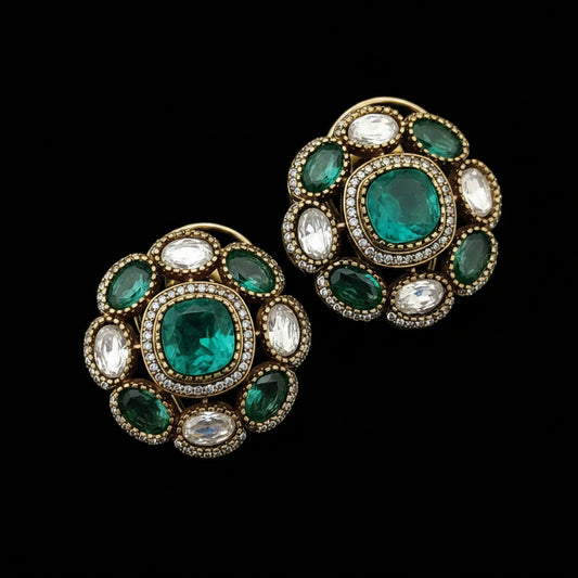 Pair of ornate earrings with green gemstones and 'SJNX-CODE-R-135' text on a light gray background.