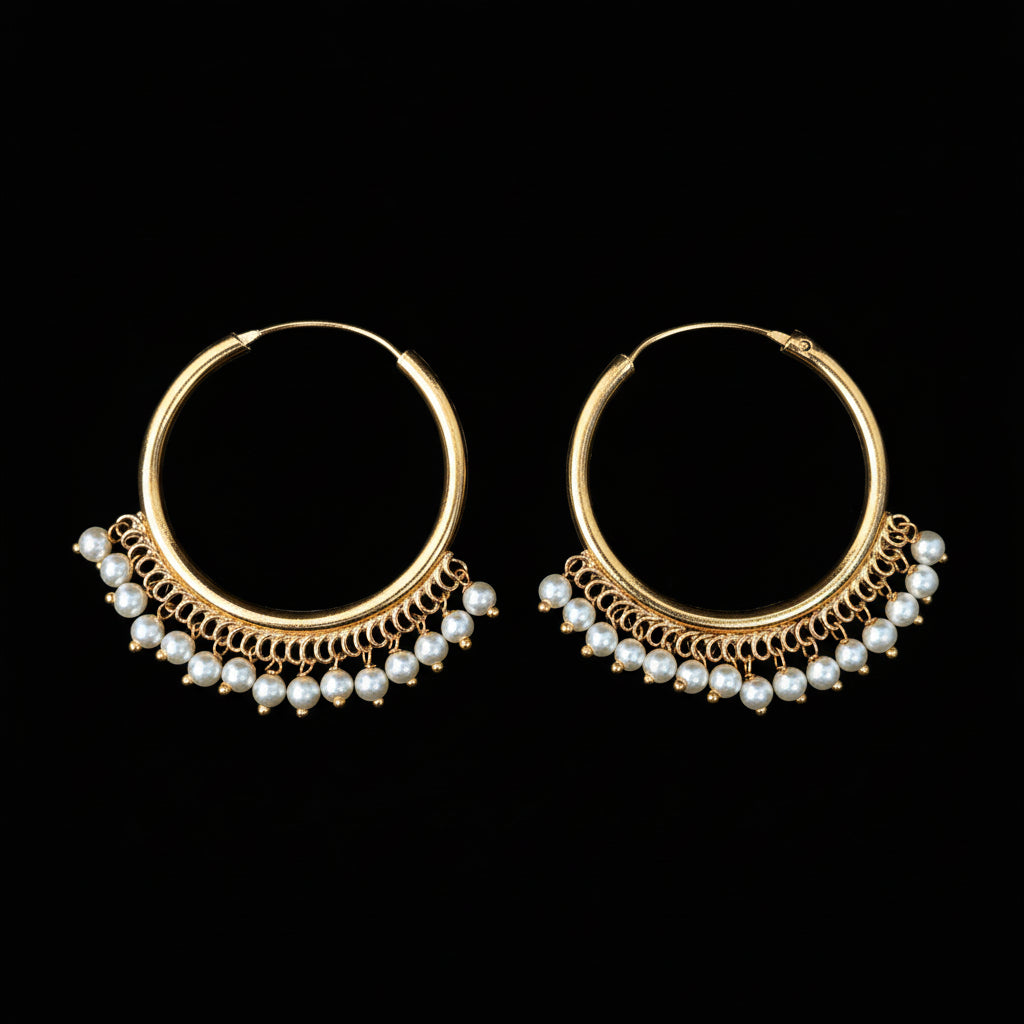 Gold hoop earrings with pearl accents on a dark background, featuring the 'Saheli' brand.