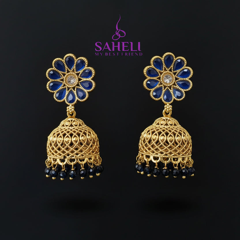 Gold and blue floral earrings on a gray stand with 'Saheeli' branding.