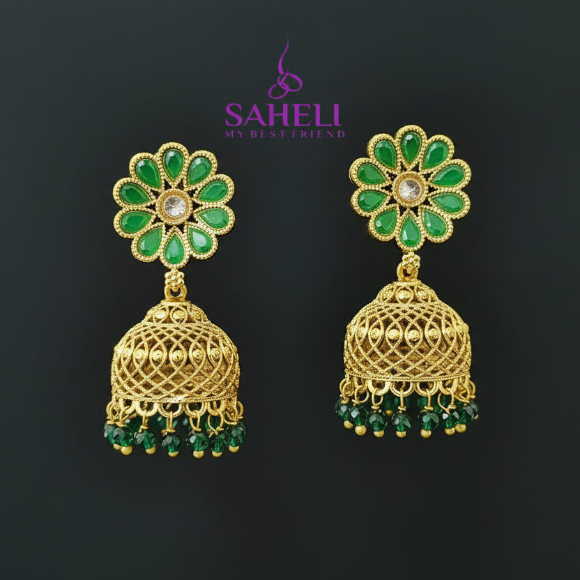 Gold and green earrings on a gray stand with 'SAHELI' branding.