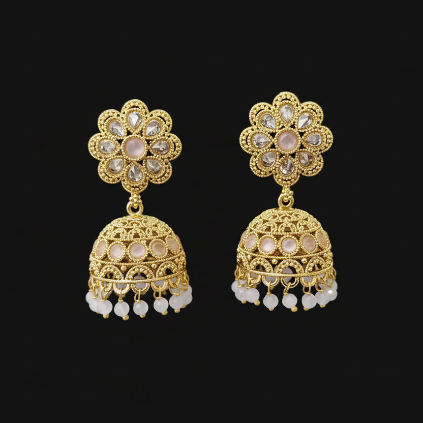 Gold earrings with floral design on a gray stand against a black background