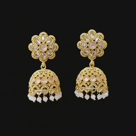 Gold earrings with floral design on a gray stand against a black background