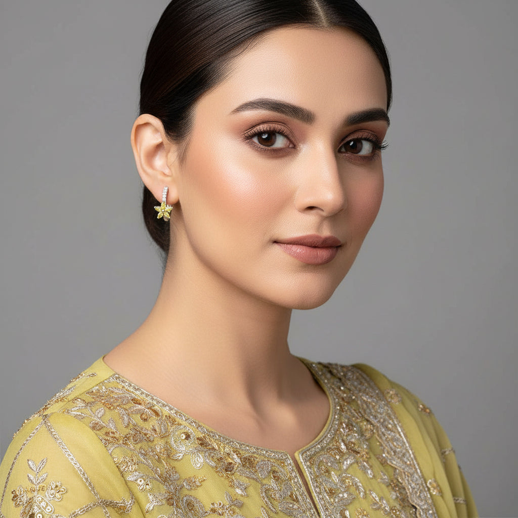 Silver ear cuffs with yellow gemstones on a gray background, featuring the brand 'SAHELI'.
