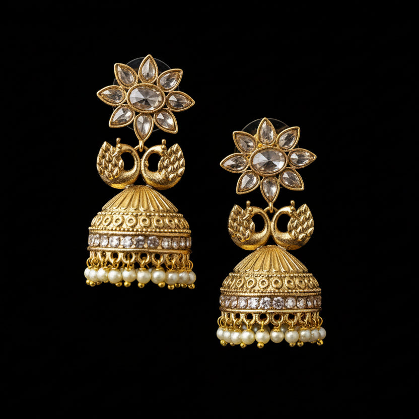 Gold earrings on a gray stand with 'SAHELI' branding.