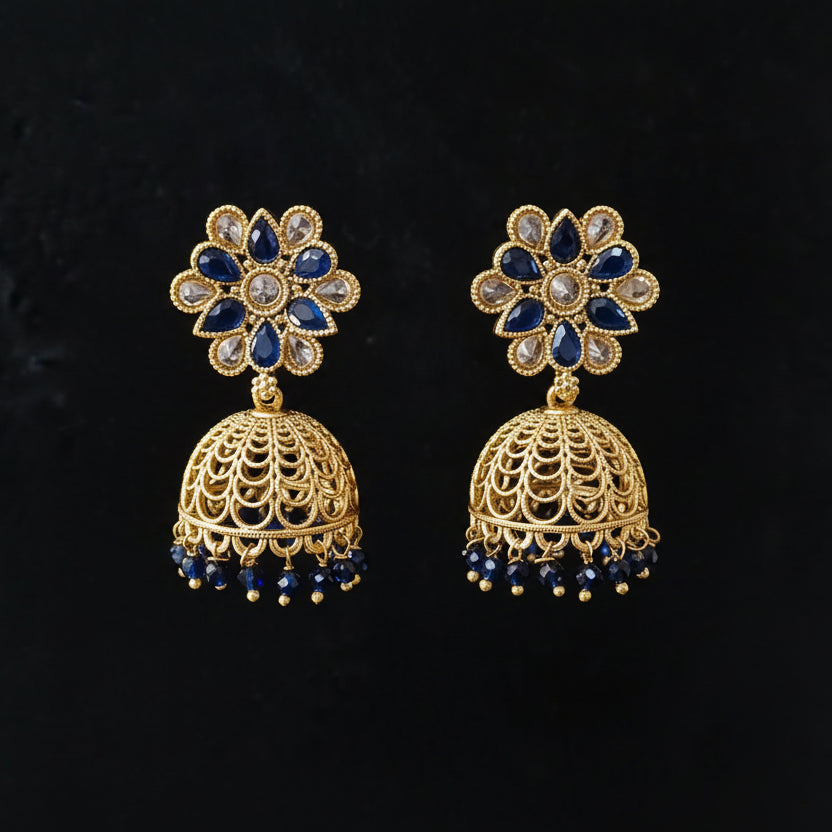 Gold and blue beaded earrings on a gray stand against a black background