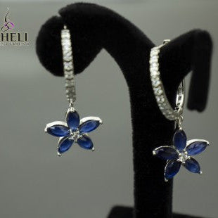 Flower-shaped earrings on a black stand with 'Sahelli' branding.