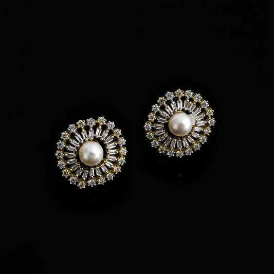 Pair of gold and pearl earrings on a dark background with 'Saheli' branding.
