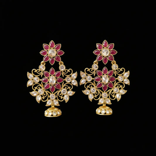 A pair of gold-toned Indian jhumka earrings with red and white stones, displayed on a gray stand with the brand logo 'SAHELL MY BEST FRIEND' above them.