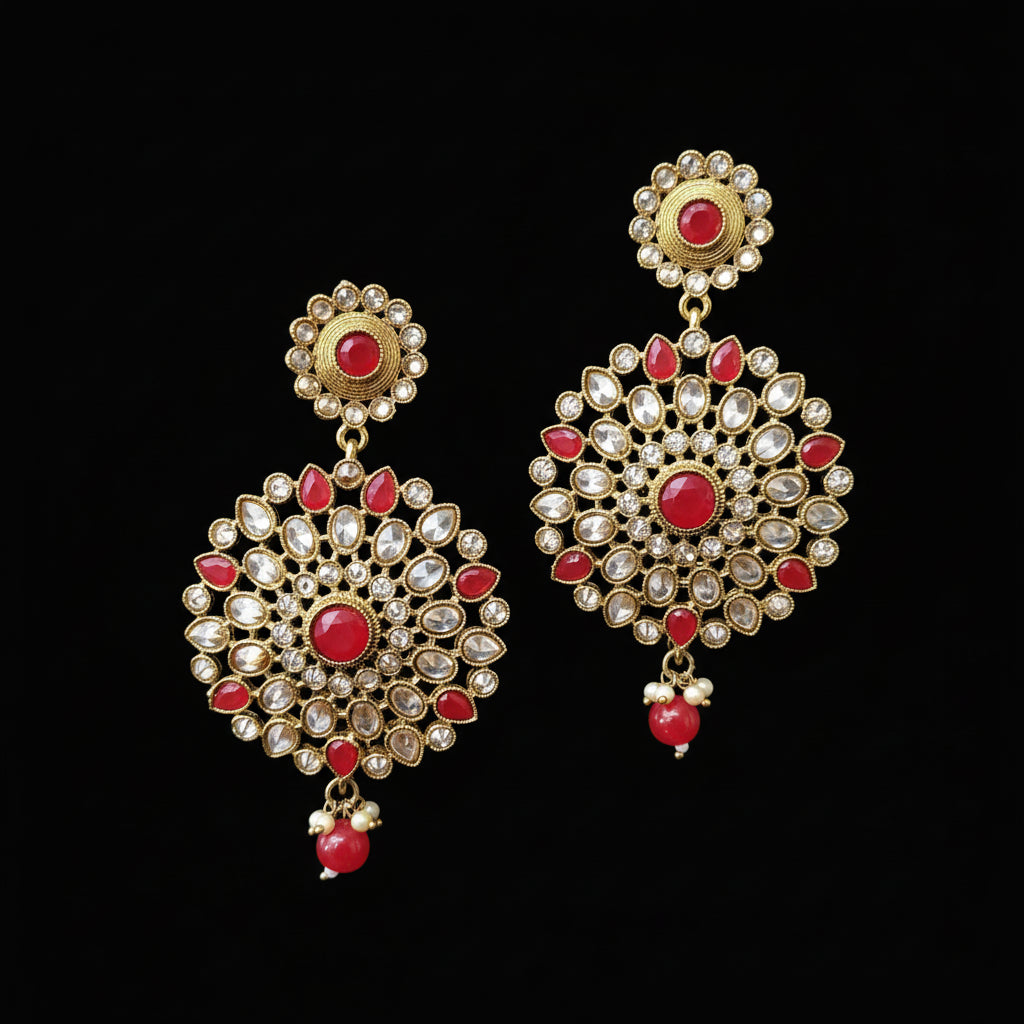 Gold and red earrings on a gray stand with 'Saheli' branding.