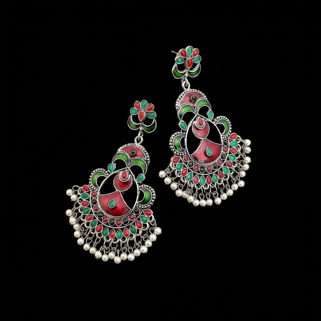 Ornate earrings with red, green, and silver design on a gray background, featuring the brand 'SAHELI'.
