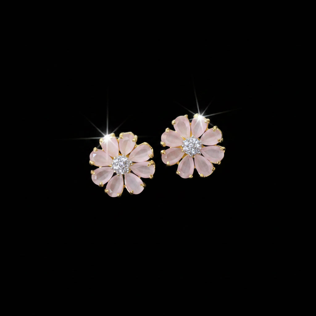 Flower-shaped earrings with pink petals and gold accents on a gray surface.