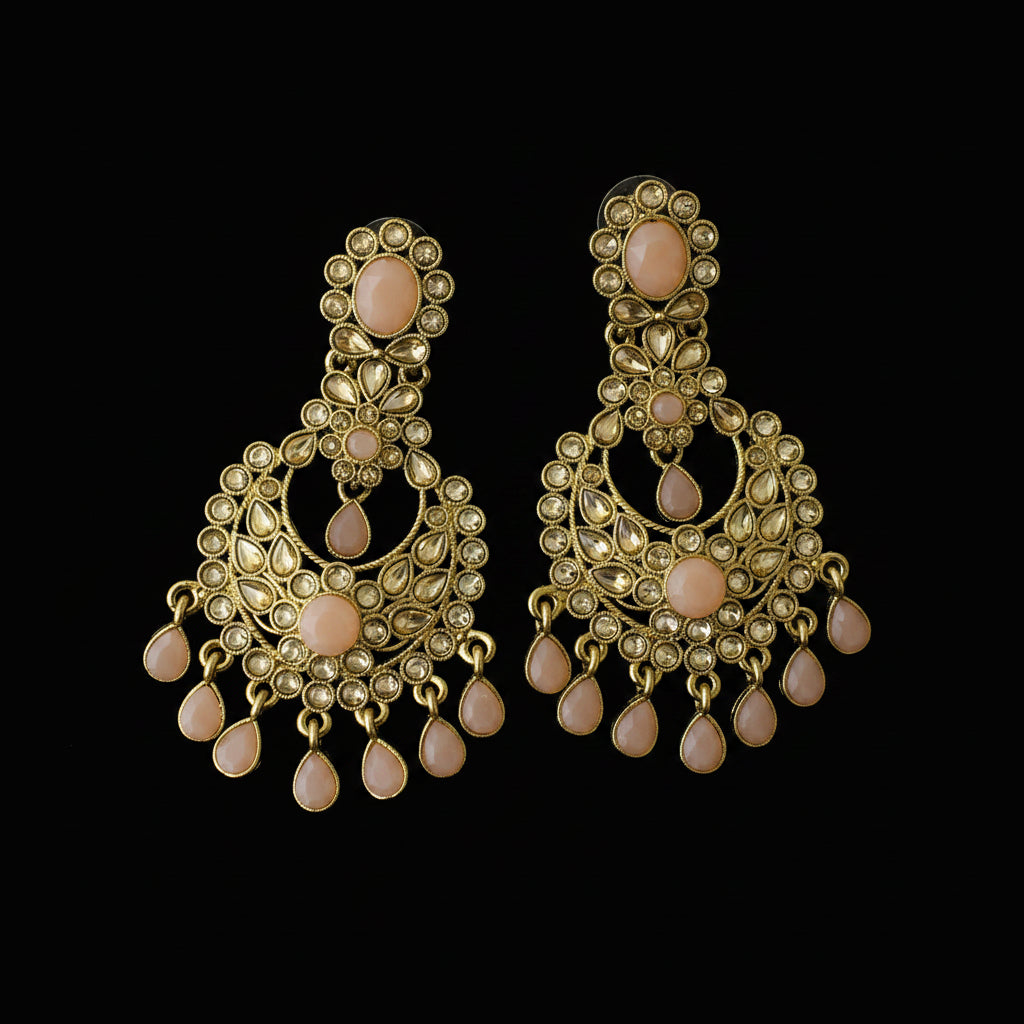 A pair of gold-toned traditional Indian chandelier earrings with peach-pink stone accents, displayed on a dark reflective surface. The brand logo 'SAHELI MY BEST FRIEND' is visible in the top left corner.