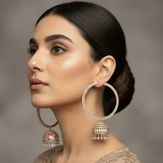 Gold hoop earrings with jhumka designs on a black stand, branded 'SAHELI'.
